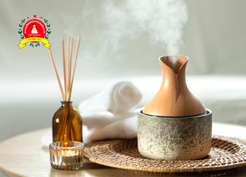 Essential oil diffuser releasing aromatic mist beside reed diffusers and a candle in a relaxing home setting, illustrating the use of essential oils for air purification and fresh indoor air.